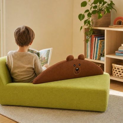 Kind liest auf dem Kindersofa Bär